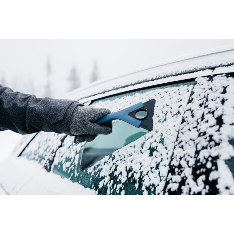Mid is isskraberen i brug på bilens rude som er sne dækket